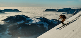 Solo skier off piste, caught mid turn, above the clouds and above some mountains Ross Woodhall - Action & Lifestyle Photography