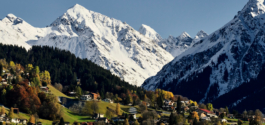 First snow on the Alps, with autumnal tree colours in the foreground with houses and greenery. Ross Woodhall - Action & Lifestyle Photography