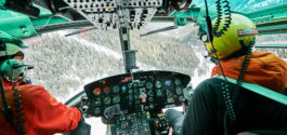 internal view of inside of a helicopter flying through a valley with snow covered pine trees. With pilot and co pilot in image. Ross Woodhall - Action & Lifestyle Photography