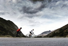 2 Cyclists on road bikes cycling along a road one behind each other in an open mountain landscape. Ross Woodhall - Action & Lifestyle Photography