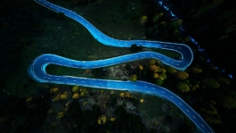 Winding road through autumnal trees in the Alps Ross Woodhall - Action & Lifestyle Photography