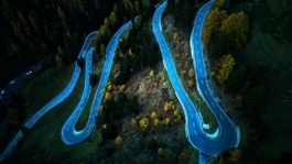 Winding road through autumnal trees in the Alps Ross Woodhall - Action & Lifestyle Photography