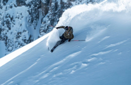 Lone skier, off piste with a huge roaster of snow behind him doing a turn on a snowy ledge Ross Woodhall - Action & Lifestyle Photography
