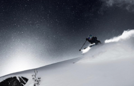 Skier off piste coming across the slope with snow particles in the air, making it look like its shot at night with stars in the sky. Ross Woodhall - Action & Lifestyle Photography
